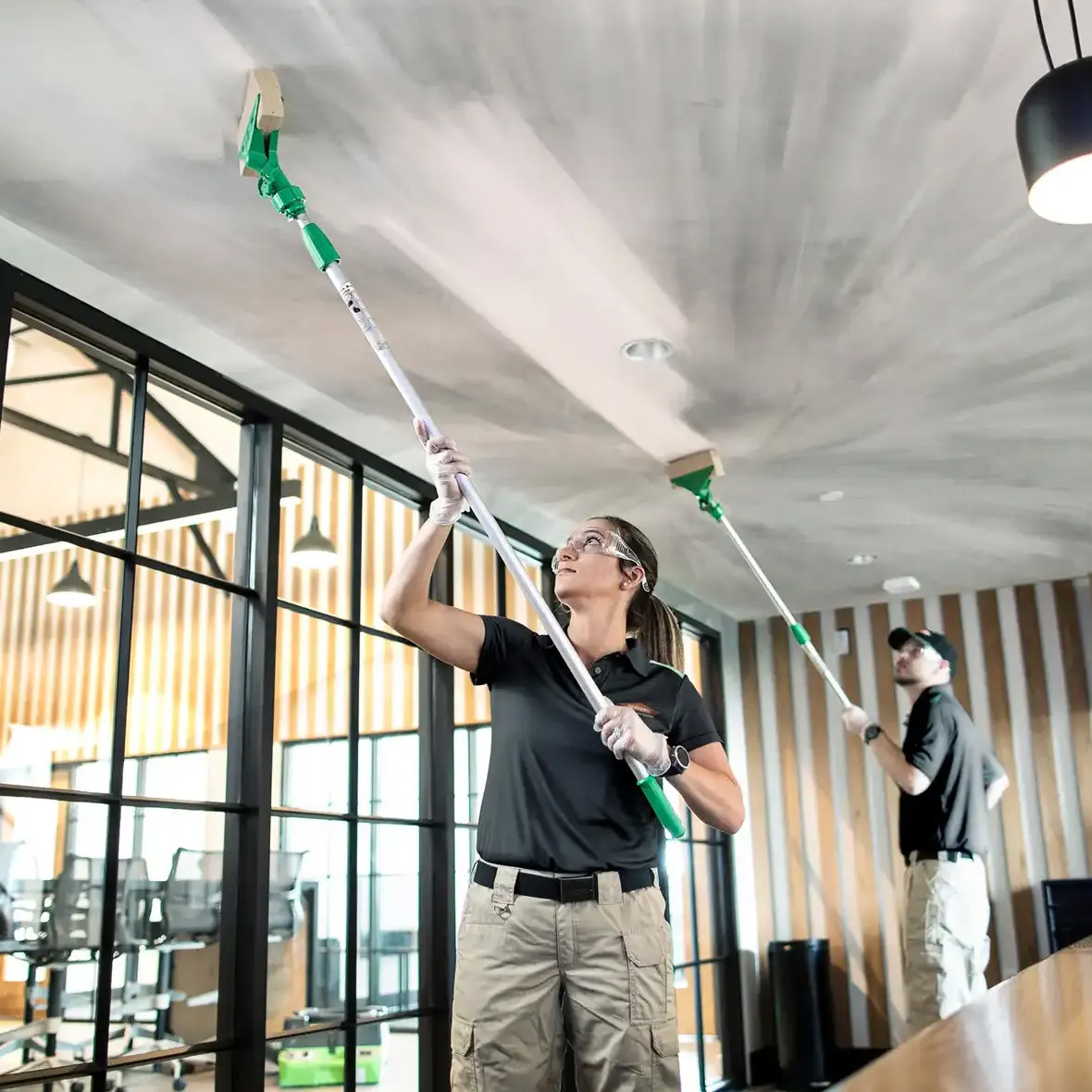 SERVPRO technicians cleaning a ceiling with extended tools
